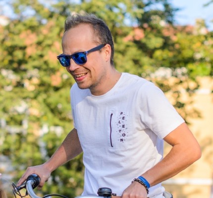 A smiling man on a bike with a white T-Shirt and blue sunglasses A smiling man on a bike with a white T-Shirt and blue sunglasses