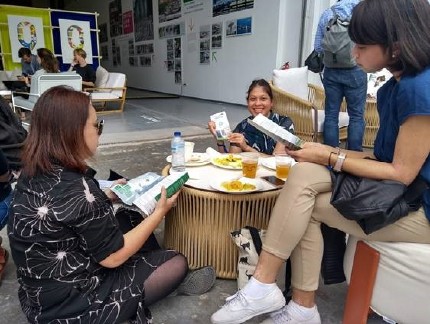 Three POC woman sitting around a coffee table, one of which is on the floor on a cushion. Another one is reading a LOW CARB pamphlet 