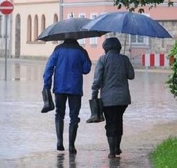 Picture of two people using an umbrella together walking on the street 
