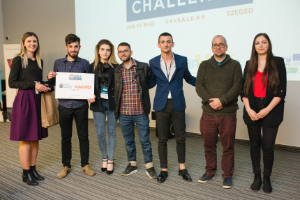 Group of people with young man holding an award placard Group of people with young man holding an award placard